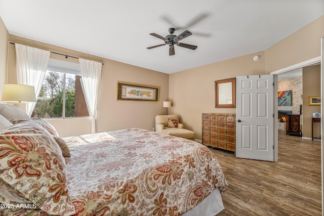 bedroom with hardwood / wood-style flooring, a fireplace, and ceiling fan