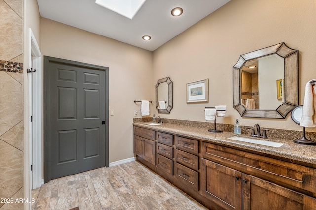 bathroom with vanity, a skylight, and hardwood / wood-style floors