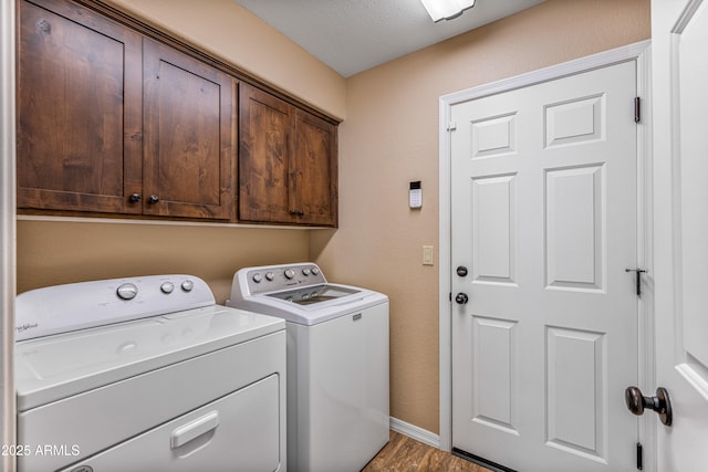 washroom with cabinets, a textured ceiling, washer and dryer, and light hardwood / wood-style flooring