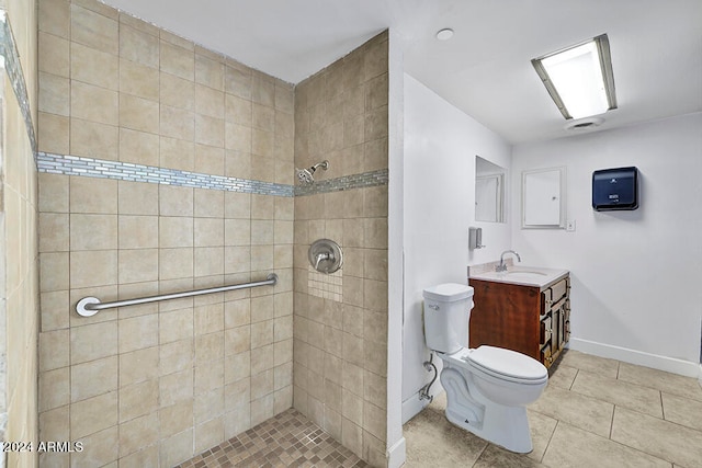 bathroom featuring tile flooring, tiled shower, vanity, and toilet