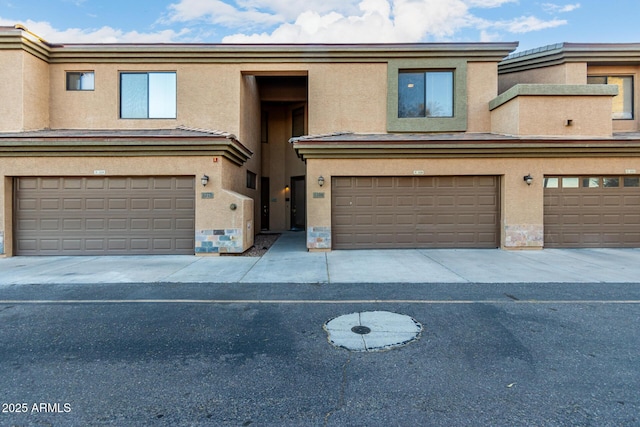 multi unit property with an attached garage and stucco siding