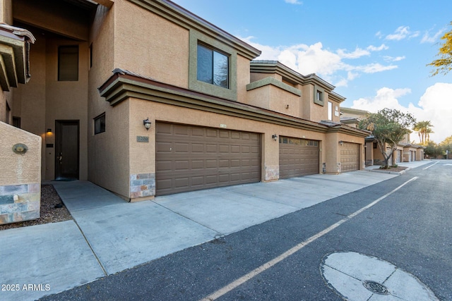 view of property exterior with an attached garage, stone siding, and stucco siding