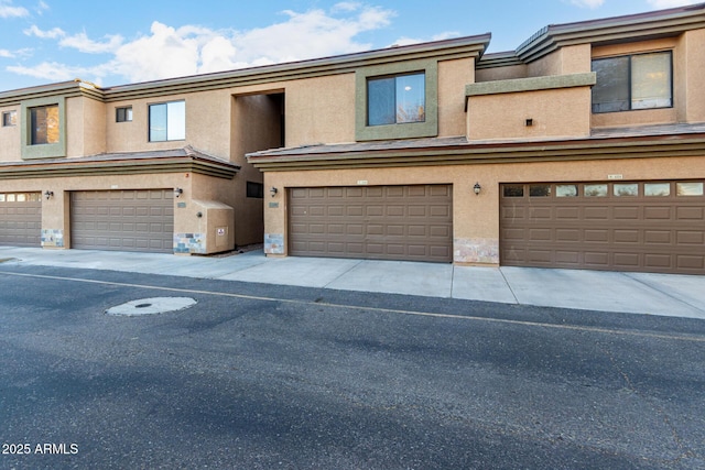 townhome / multi-family property with a garage and stucco siding