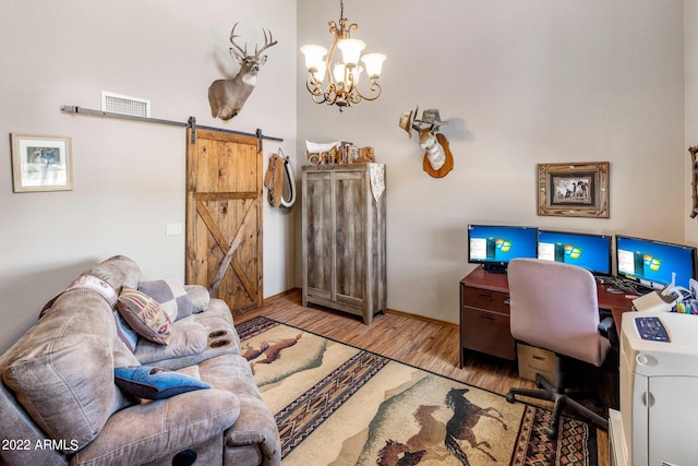 office featuring a notable chandelier, a barn door, and light hardwood / wood-style flooring