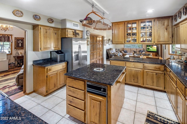 kitchen with a kitchen island, stainless steel refrigerator with ice dispenser, light tile patterned floors, and a wealth of natural light