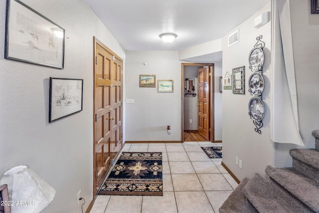 hall with light tile patterned flooring and a textured ceiling