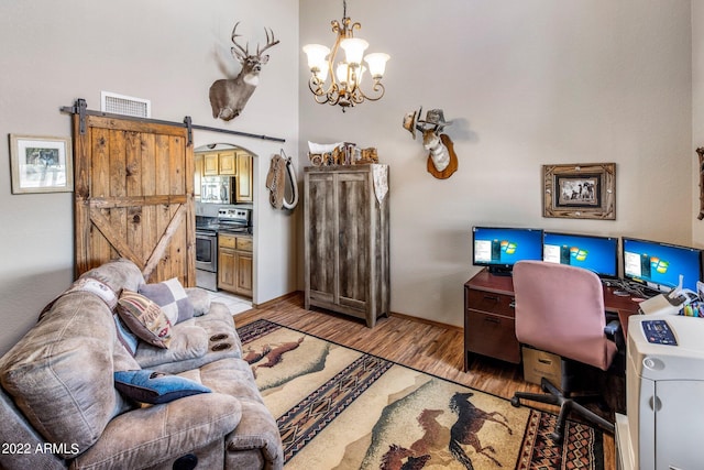 home office featuring a chandelier, light hardwood / wood-style flooring, and a barn door