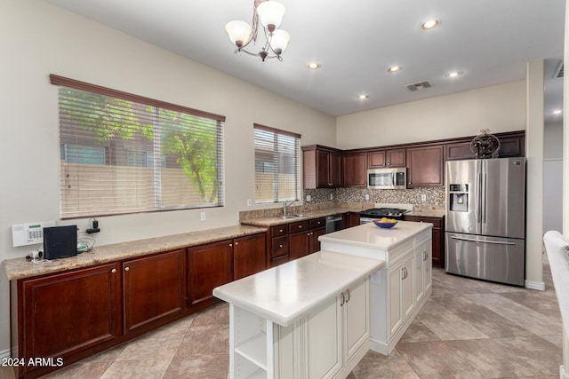 kitchen with hanging light fixtures, stainless steel appliances, backsplash, a chandelier, and a kitchen island