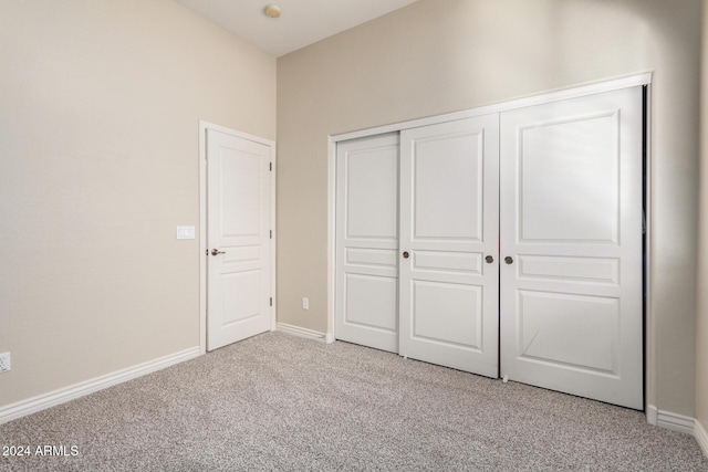 unfurnished bedroom with light carpet and a closet