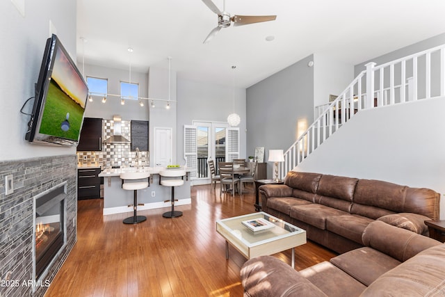15221 N Clubgate Dr Unit 2059, Scottsdale, AZ 85254 - living room with ceiling fan, a high ceiling, hardwood / wood-style flooring, a glass covered fireplace, and stairs