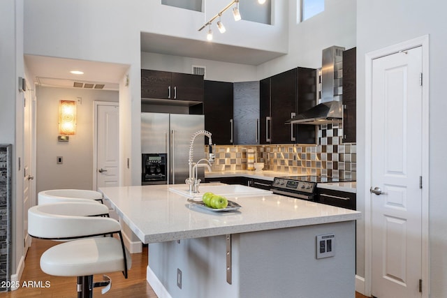 15221 N Clubgate Dr Unit 2059, Scottsdale, AZ 85254 - kitchen featuring high end refrigerator, wall chimney exhaust hood, electric stove, a towering ceiling, and a kitchen island with sink