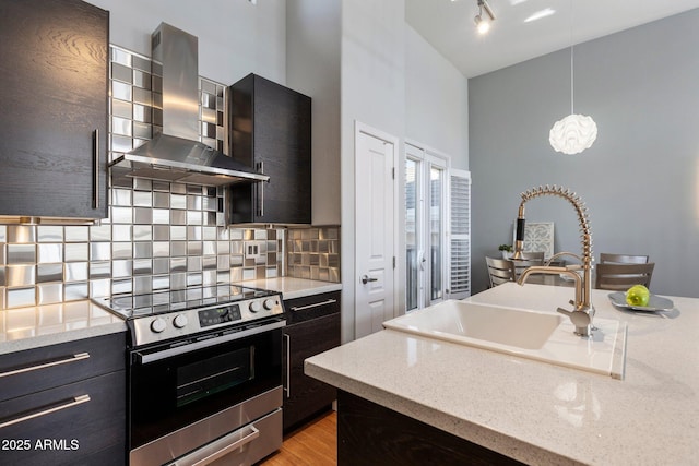 15221 N Clubgate Dr Unit 2059, Scottsdale, AZ 85254 - kitchen with stainless steel range with electric cooktop, wall chimney exhaust hood, a towering ceiling, tasteful backsplash, and hanging light fixtures