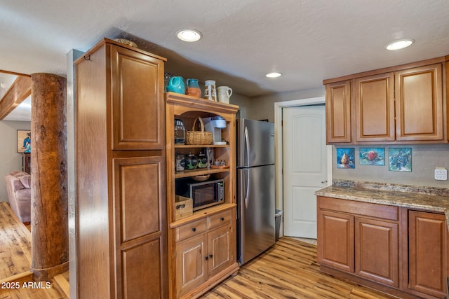 kitchen with stainless steel appliances, light hardwood / wood-style floors, and light stone counters