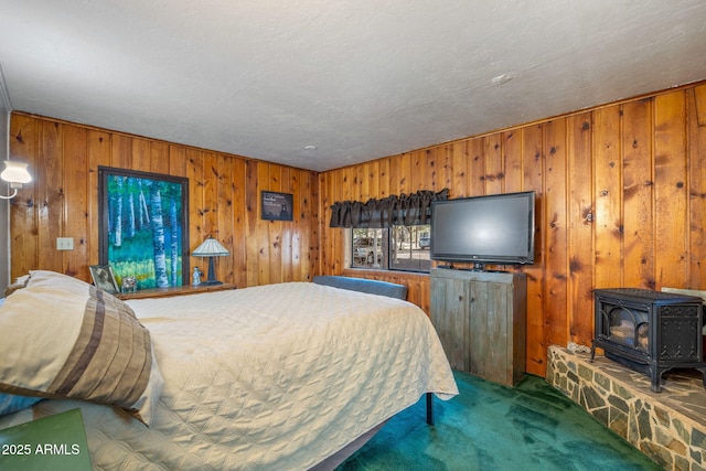 bedroom featuring a textured ceiling, carpet floors, wooden walls, and a wood stove