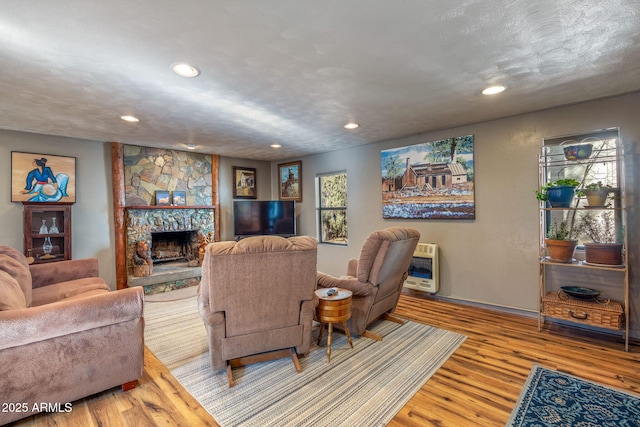 living room with a fireplace, light wood-type flooring, a textured ceiling, and heating unit