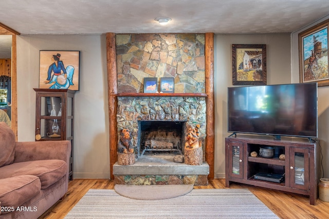 living room with a fireplace, light wood-type flooring, and a textured ceiling