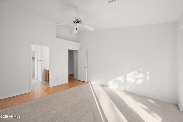 unfurnished bedroom featuring ensuite bathroom, high vaulted ceiling, ceiling fan, and light hardwood / wood-style floors