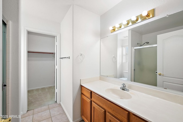 bathroom featuring toilet, a shower with door, vanity, and tile patterned flooring