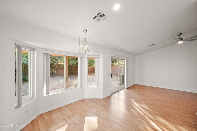 unfurnished room featuring a healthy amount of sunlight, ceiling fan with notable chandelier, and light wood-type flooring