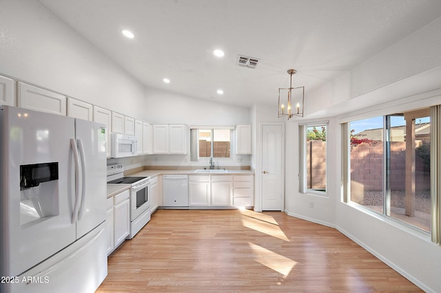 kitchen featuring pendant lighting, white appliances, sink, a notable chandelier, and white cabinetry