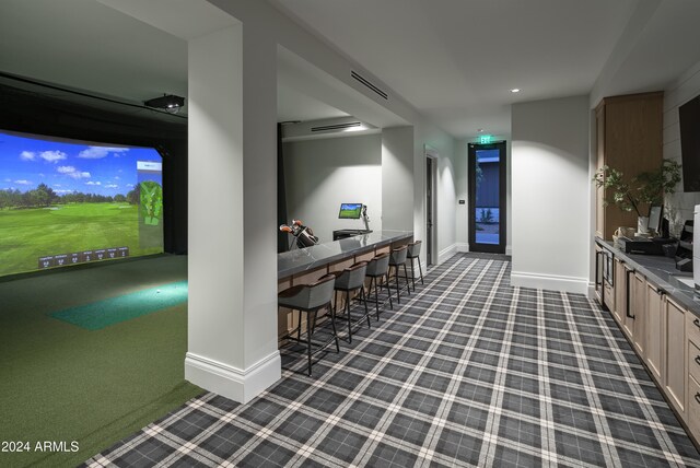 interior space with golf simulator, dark carpet, and light brown cabinets