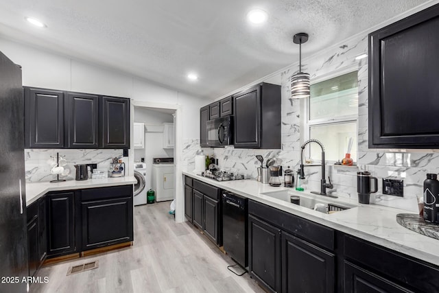 kitchen with dark cabinetry, decorative backsplash, a sink, and black appliances