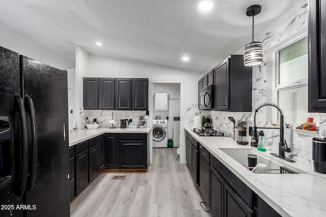 kitchen featuring washer / dryer, lofted ceiling, a sink, backsplash, and black appliances