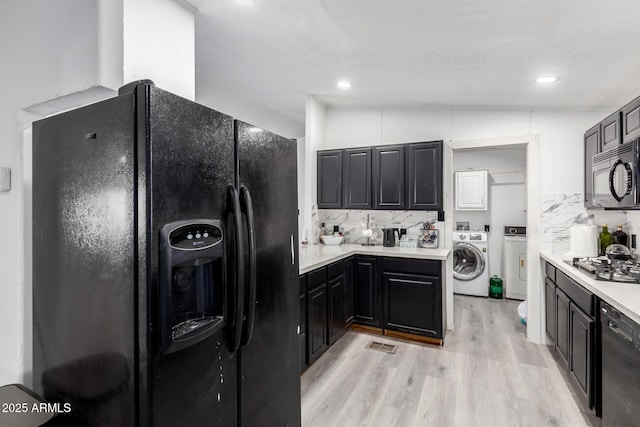kitchen with washer / dryer, black appliances, and tasteful backsplash