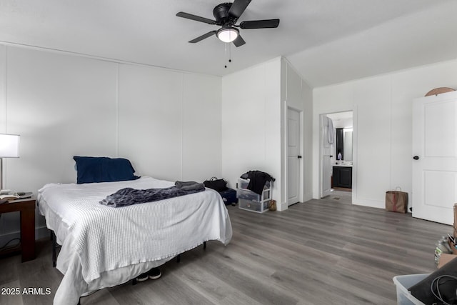 bedroom featuring ceiling fan, a decorative wall, ensuite bath, and wood finished floors