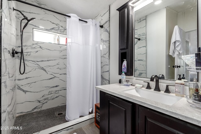 bathroom with a marble finish shower and vanity