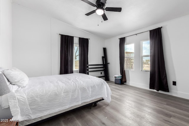 bedroom with baseboards, multiple windows, wood finished floors, and lofted ceiling