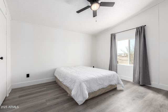 bedroom featuring baseboards, ceiling fan, wood finished floors, and vaulted ceiling