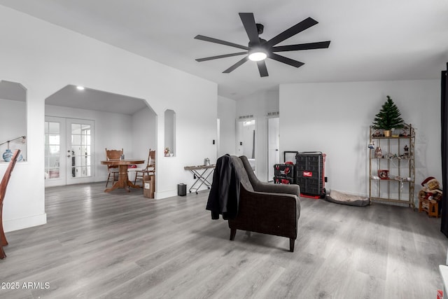 living room featuring baseboards, arched walkways, ceiling fan, and wood finished floors