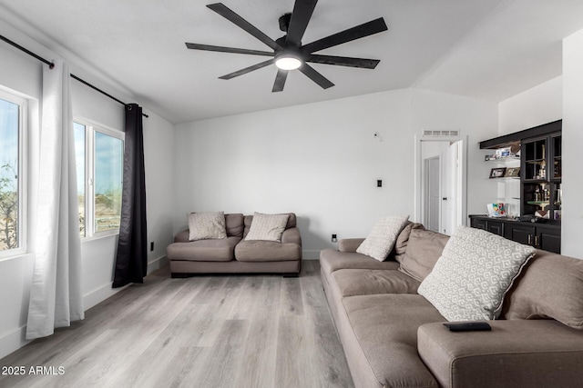 living area with ceiling fan, visible vents, baseboards, lofted ceiling, and light wood-style floors