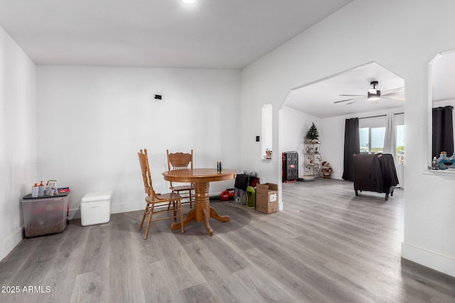 dining room with arched walkways, baseboards, ceiling fan, and wood finished floors