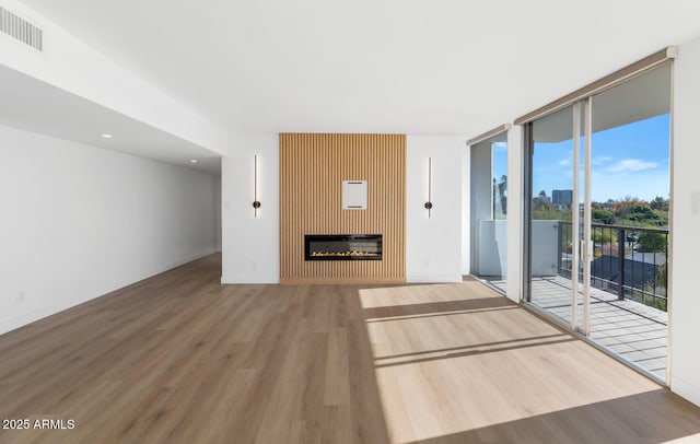 unfurnished living room with a fireplace, floor to ceiling windows, and hardwood / wood-style flooring