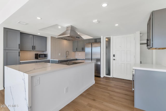 kitchen featuring appliances with stainless steel finishes, a kitchen island, sink, gray cabinets, and island range hood