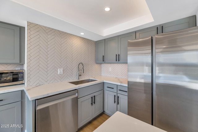 kitchen featuring appliances with stainless steel finishes, decorative backsplash, light stone counters, and sink