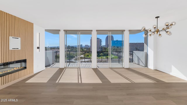 unfurnished living room with floor to ceiling windows, light hardwood / wood-style flooring, and a notable chandelier