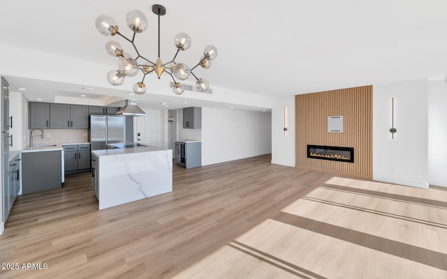 kitchen with backsplash, decorative light fixtures, a large fireplace, a kitchen island, and sink