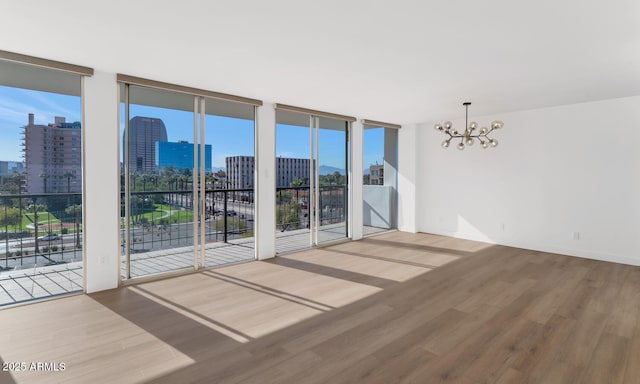 spare room featuring a chandelier, hardwood / wood-style flooring, and expansive windows