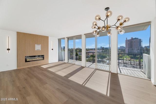 unfurnished living room with floor to ceiling windows, hardwood / wood-style floors, a chandelier, and a fireplace