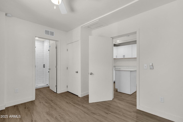 unfurnished bedroom featuring connected bathroom, ceiling fan, a closet, and light hardwood / wood-style floors