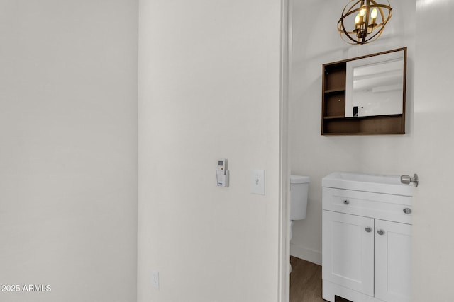 bathroom with a chandelier, wood-type flooring, vanity, and toilet