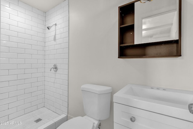 bathroom with vanity, toilet, and tiled shower