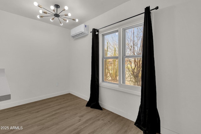 empty room with a chandelier, a wall mounted air conditioner, and wood-type flooring