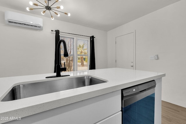 kitchen featuring dishwashing machine, a wall mounted AC, sink, hardwood / wood-style flooring, and a chandelier