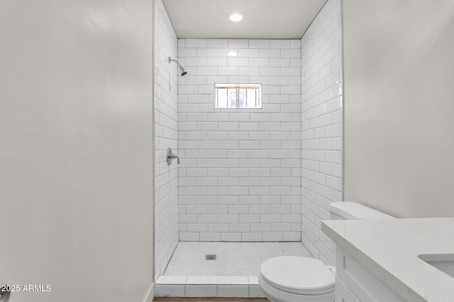 bathroom with vanity, toilet, and tiled shower