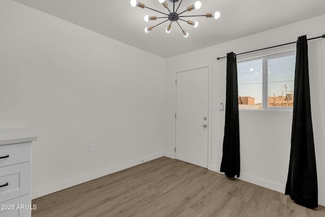 spare room featuring a chandelier and light hardwood / wood-style floors