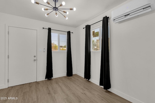 interior space with a chandelier, a wall unit AC, and light hardwood / wood-style flooring